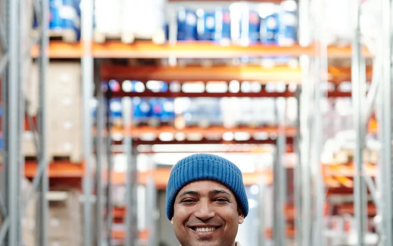 A warehouse worker smiling between the racks