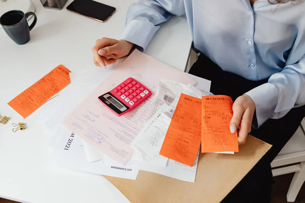 Office manager sorting receipts and invoices with a calculator